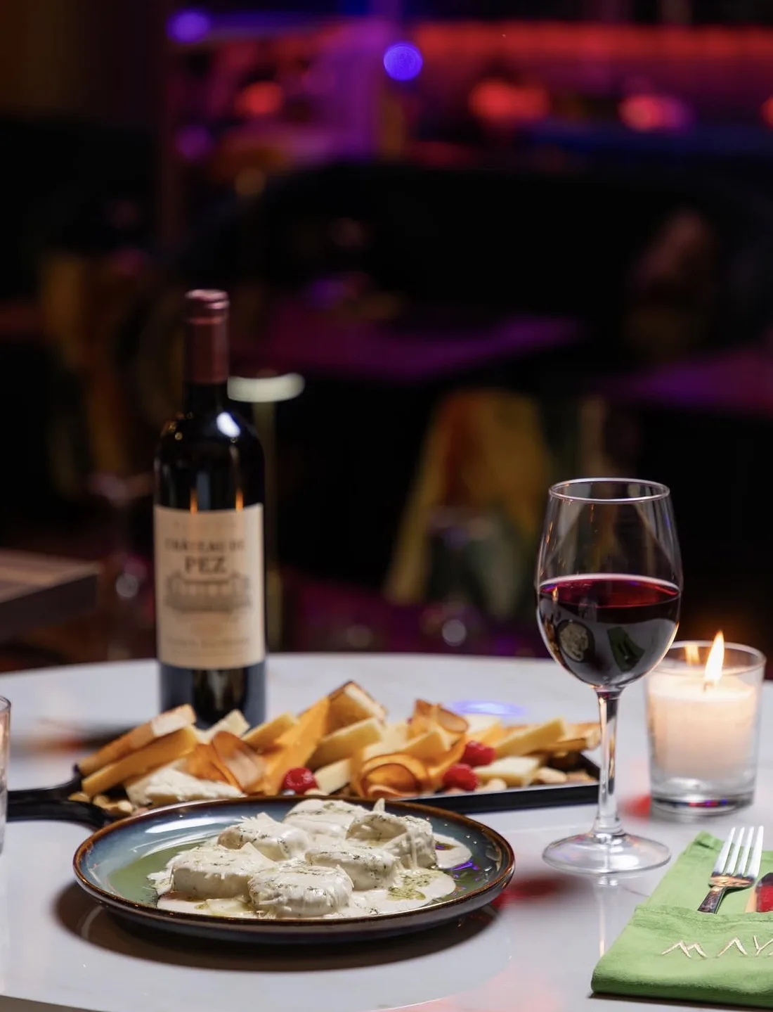 A table at MAYA: wine, cheese and the room glowing behind